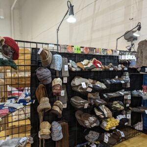 booth at a fiber festival showing hats, fiber, and yarn made from alpaca fiber