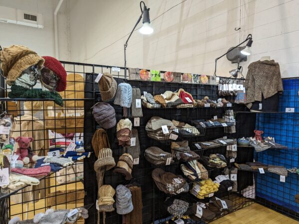 booth at a fiber festival showing hats, fiber, and yarn made from alpaca fiber