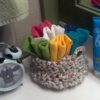 Crocheted basket of white yarn holding colorful washcloths