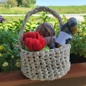 Crocheted basket in thick white yarn holding skeins of colorful yarn